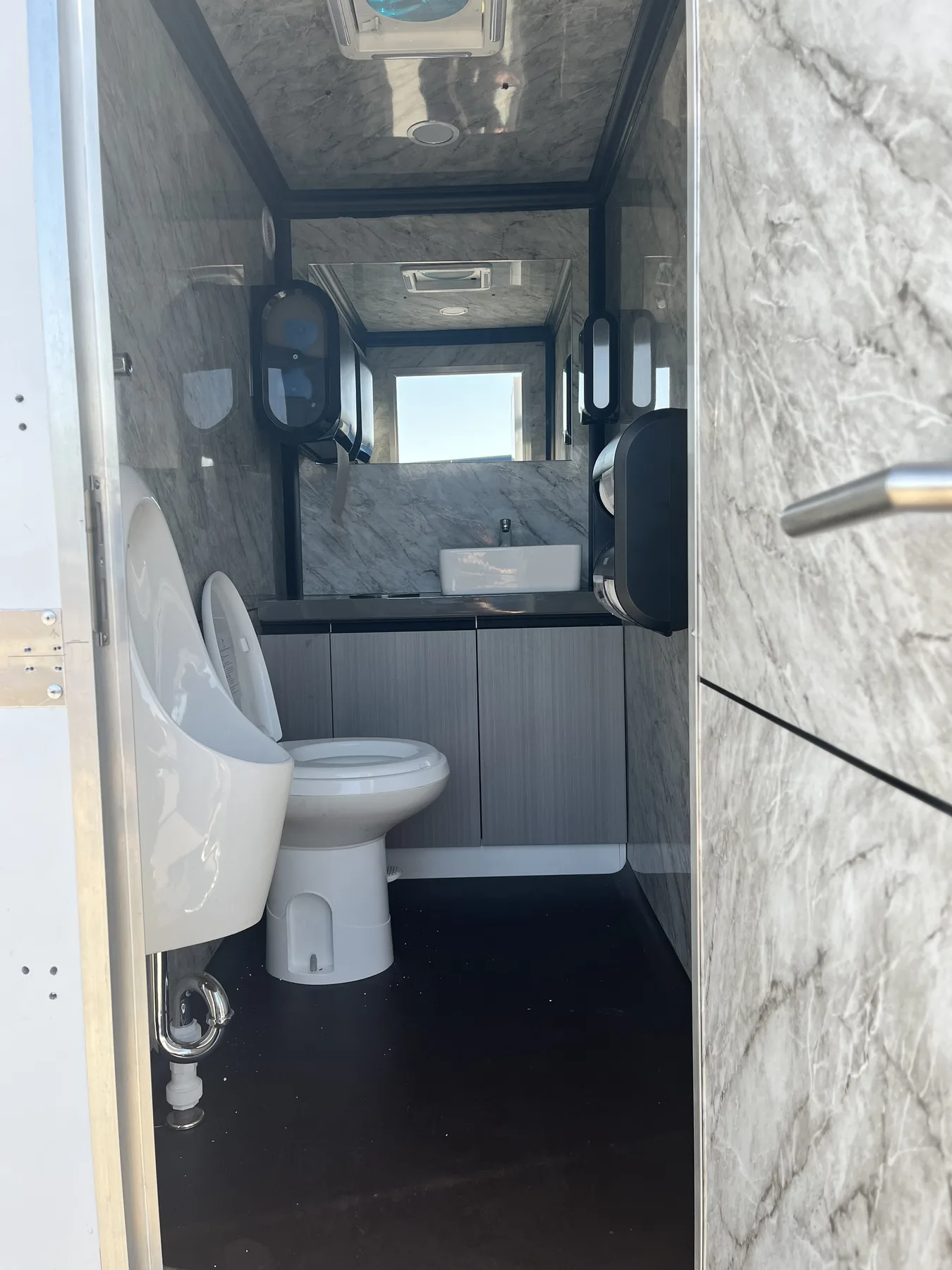 Trailer stall with marble-look walls, urinal and vanity